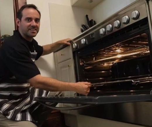 Scott, owner of Ace Oven Cleaning, cleaning an oven in a customer's kitchen